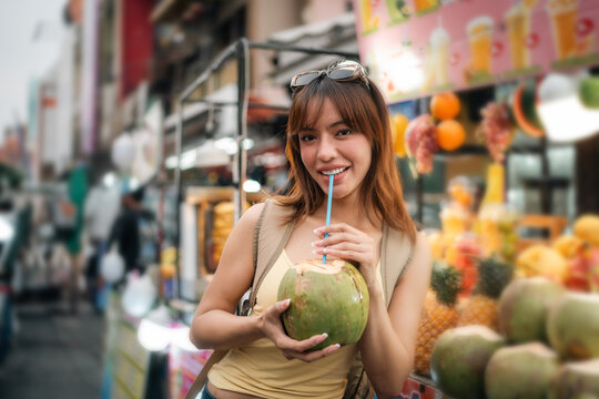 Young woman enjoy eating street food at night market. Traveler blogger women Happy tourists Beautiful female with Traditional food local road at thailand bangkok city.