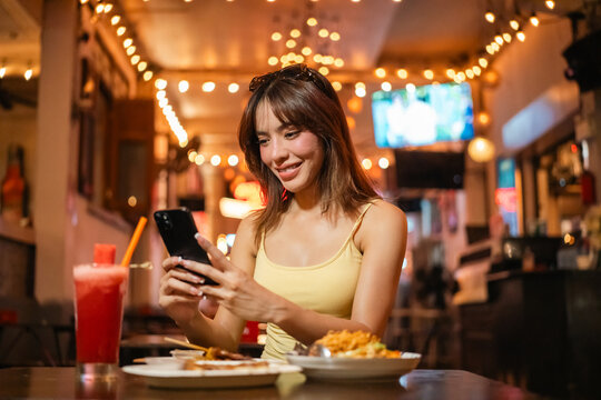 Young woman enjoy eating street food at night market. Traveler blogger women Happy tourists Beautiful female with Traditional food local road at thailand bangkok city.