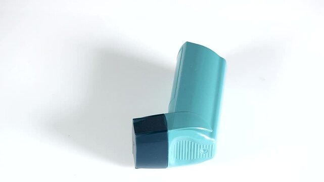 Blue asthma inhaler rotating on white background