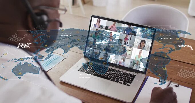 Headset-wearing man writing notes during health meeting, laptop loading data revealing animated map