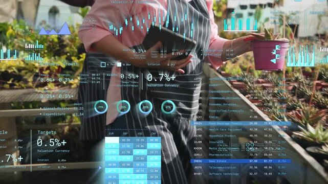 Greenhouse worker tapping tablet and inspecting succulents, HUD charts updating for stock checks