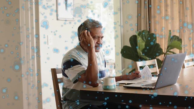 Senior man holding letter, touching ear, spurring bill checking online while blue dots overlaying