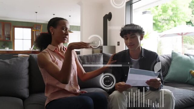 Mother and son reading papers on sofa, woman pointing and sparking confetti, celebrating school