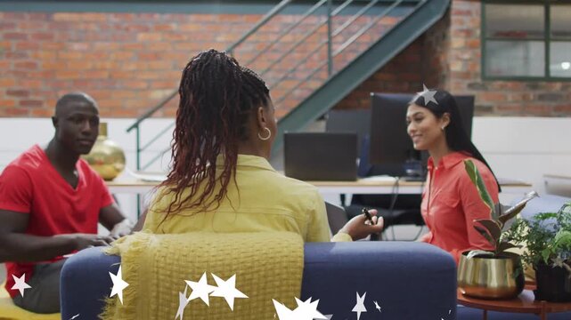 Person in yellow extending pen initiating office chat, woman in coral smiling, stars fading on sofa