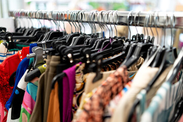 Fototapeta premium Clothes rack with fashion items and hangers in a retail clothing store