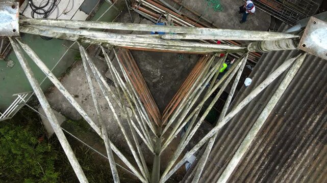op Down Aerial Shot With Slight Travel of Unrecognizable Technician Climbing Half Built Antenna Tower 4K