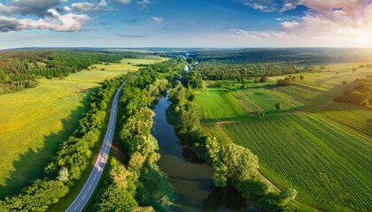 Naklejka premium scenic country road winds through landscape under a summer sky surrounded by green fields and trees beautiful drone aerial view landscape of green nature cultivated agricultural farm and river