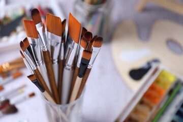 Paint brushes, paints and palette on light grey table, closeup. Space for text © New Africa