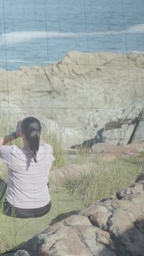 Vertical video: Woman on coast after holding pose lowering arms for health, green overlaying torso