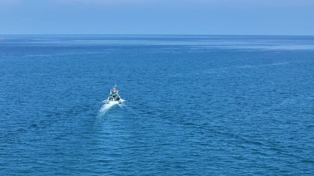 Small Boat Sailing Across Vast Blue Sea Under Clear Sky, Creating Serene and Peaceful Scene on Ocean Horizon