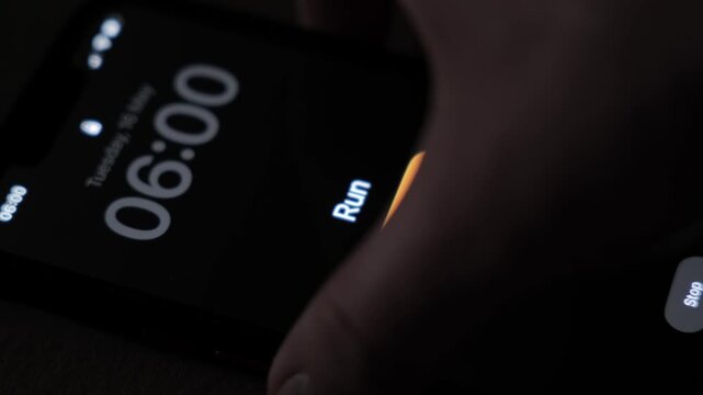 A phone alarm is active at 6 AM with the run text on a dim screen and a visible snooze button showing an early wake up moment for a morning run. High quality 4k footage