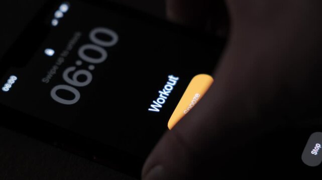 A phone alarm is active at 6 AM with the workout text on a dim screen and a visible snooze button showing an early morning fitness wake up routine. High quality 4k footage