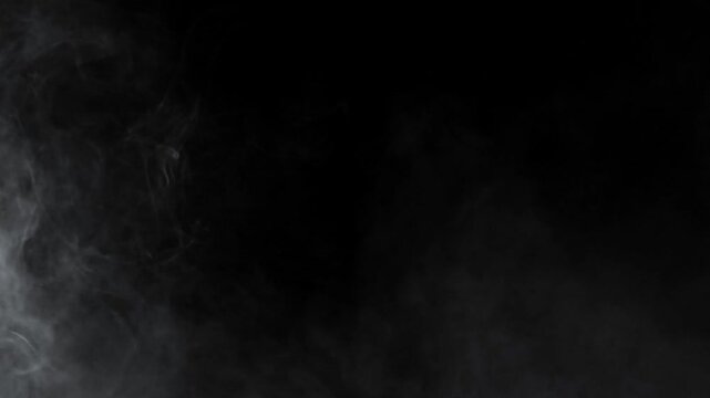 Subtle fog appears in opposite corners, framing the empty black space. Atmospheric overlay for cinematic titles, horror, or suspenseful scenes