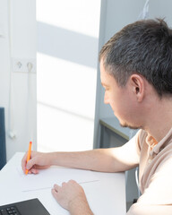 Fototapeta premium A man works at his desk at home, in a home office, writing, signing, and stamping his name