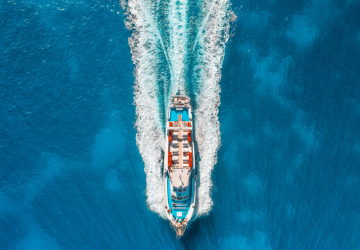 Aerial drone view of beautiful floating yacht in blue sea on sunny day in summer. Sardinia island, Italy. Top down view of boat, sea, turquoise water. Travel. Tropical landscape. Yachting. Cruise