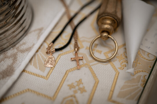 Golden orthodox cross and icon pendant on liturgical fabric for baptism ceremony in church