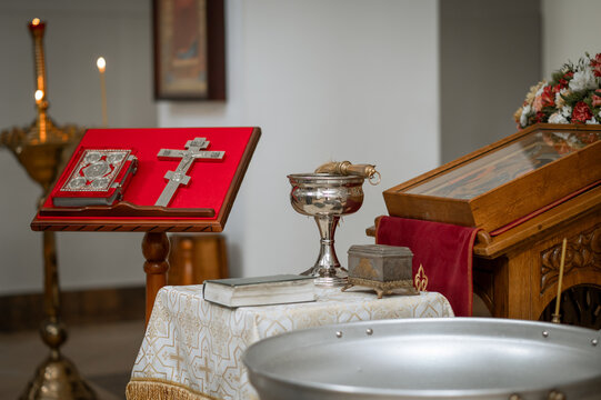 Orthodox Gospel book and silver cross on red velvet lectern in church with iconostasis background
