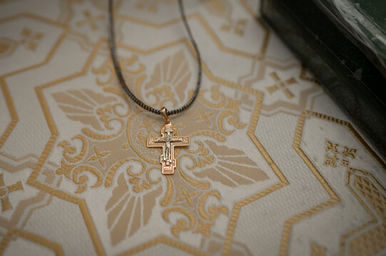 Golden orthodox cross pendant on liturgical embroidery fabric for baptism ceremony in church