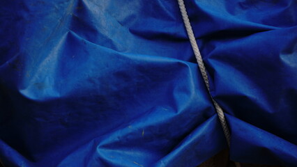 blue tarpaulin waving and white rope as a background © Esteve