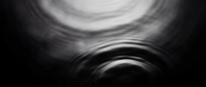 water surface with circular ripple waves in monochrome lighting natural background