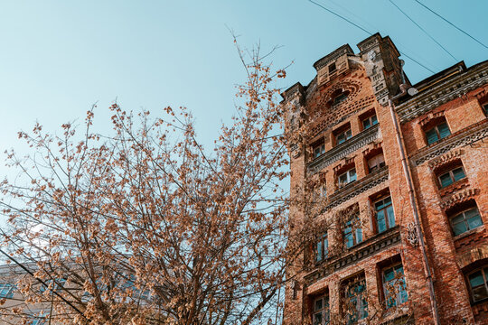 Eclectic historic building with intricate brickwork amid dry autumn branches 