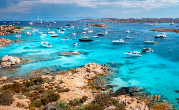 Aerial view of luxury yachts and boats on blue sea, beautiful island, mountain on summer sunny day. Sandy beach, rocky sea coast, azure transparent water in Sardinia, Italy. Top drone view. Seascape