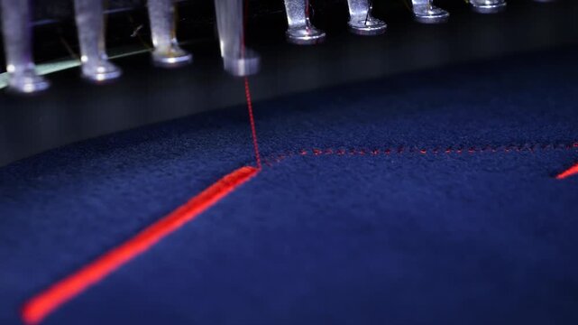 Machine embroidery on a black fleece blouse with red thread. House roof embroidery. Selective focus close-up.