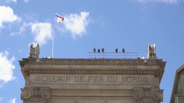 Low angle view of French flag waving on the roof of Gare du Nord station in Paris, France