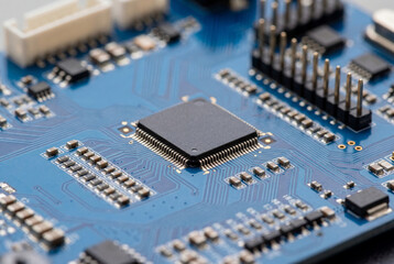Fototapeta premium Close up of black microchip on blue printed circuit board with electronic components