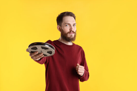 Professional actor with film reel on yellow background