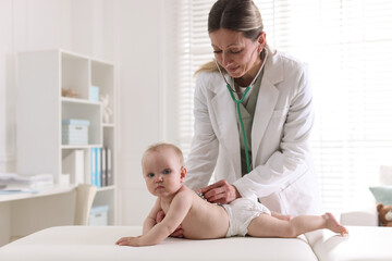 Fototapeta premium Pediatrician examining cute baby with stethoscope in hospital, space for text