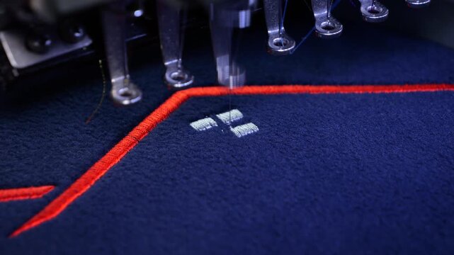 Machine embroidery on a black fleece blouse with red thread. House roof embroidery. Slow motion video. Selective focus close-up.