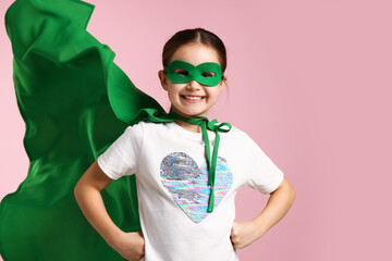 Little girl wearing superhero costume on pink background © New Africa