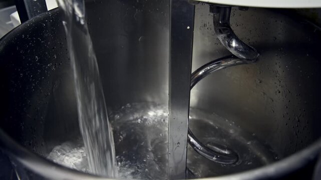 Water flows into mixing bowl for dough preparation with visible mixing attachment
