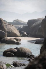 Fotobehang Grijs Massive granite boulders and calm tide pools at Boulders Beach, Simon's Town. A serene coastal landscape near Cape Town, South Africa, featuring natural rock formations and misty mountains.  © Cameron