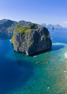 Dramatic limestone islands rise in Bacuit Bay, El Nido. This scenic area in the Philippines is a popular vacation destination due to its beautiful coral reefs, beaches, and hidden lagoons.