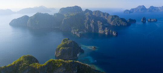 Dramatic limestone islands rise in Bacuit Bay, El Nido. This scenic area in the Philippines is a popular vacation destination due to its beautiful coral reefs, beaches, and hidden lagoons. © ead72