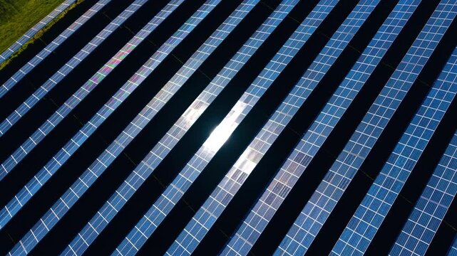 Abstract diagonal pattern of solar panels with sun glare. Diagonal rows of blue photovoltaic panels with intense central sun reflection creating a geometric industrial pattern.