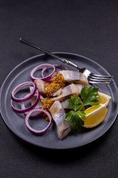 Pickled herring fillets on plate with red onion and mustard