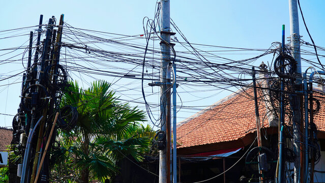 Lots of electricity wires on a pole in Bali, Indonesia.Complex network of electric wires near a building in a tropical area on a clear sunny day