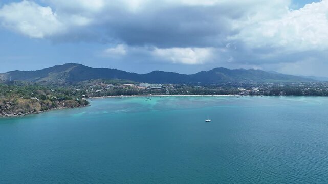Aerial View of Serene Coastal Landscape with Turquoise Waters, Lush Hills, and Distant Shoreline Under Partly Cloudy Sky