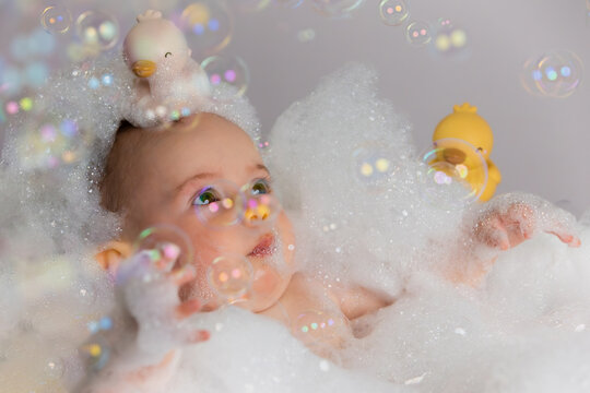 Baby enjoying a bubble bath playing with rubber ducks