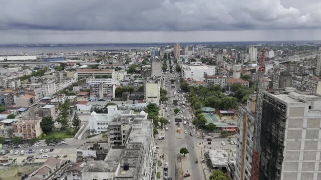 Drone flies past crane on building being renovated on main street on an overcast day in Maputo, Mozambique