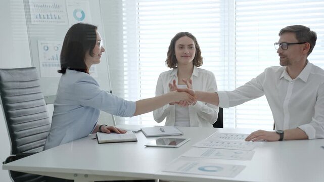 Business professionals shaking hands, sealing a deal, demonstrating partnership and trust during a corporate meeting in a modern office workplace setting