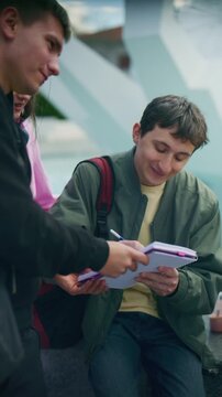 High school friends signing a notebook outdoors, sharing a happy moment. Young students enjoying friendship and interaction.