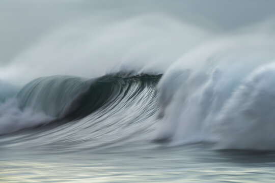 Breaking ocean wave at sunrise with motion blur effect created in camera using slow shutter speed at Bronte Beach, Sydney, Australia.