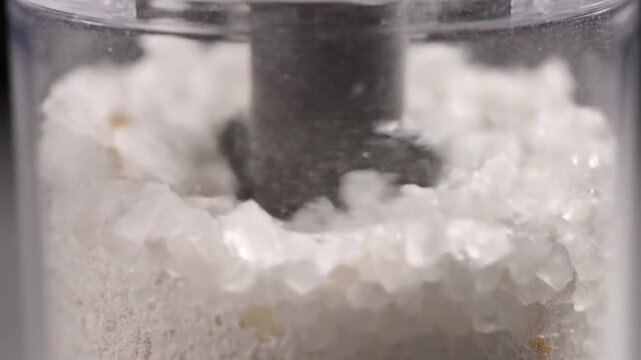 Macro Close Up of Coarse Sea Salt Being Ground in a Clear Mill