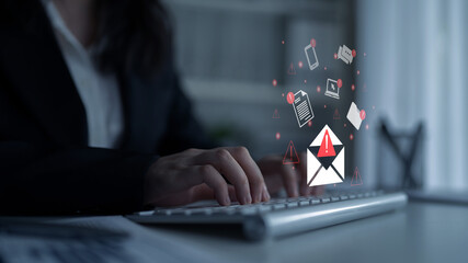 A focused businesswoman utilizes a laptop, with digital email icons and warning alerts showcased above, symbolizing modern communication and cybersecurity challenges. Gantry © InfiniteFlow