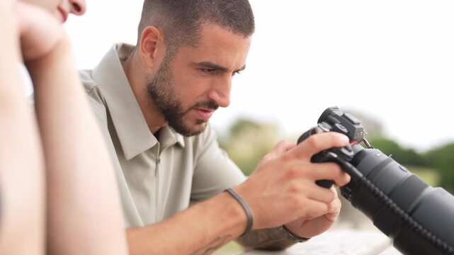 Man adjusts camera lens with focused attention. He wears a light-colored shirt and looks intently. His expression shows concentration and care. Ideal for photography tutorials or training scenarios