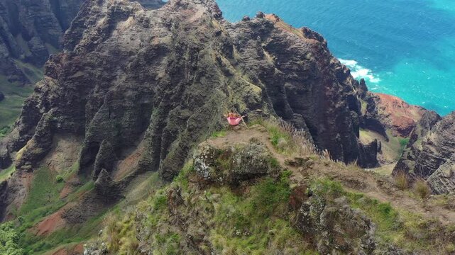Absolutely breathtaking drone shot with girl on rocky edge, Kauai, Hawaii
